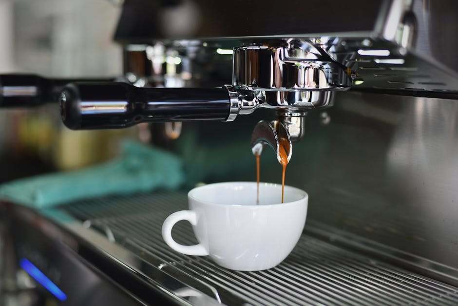 Nærbillede af en espressomaskine, der brygger kaffe i en hvid kop.