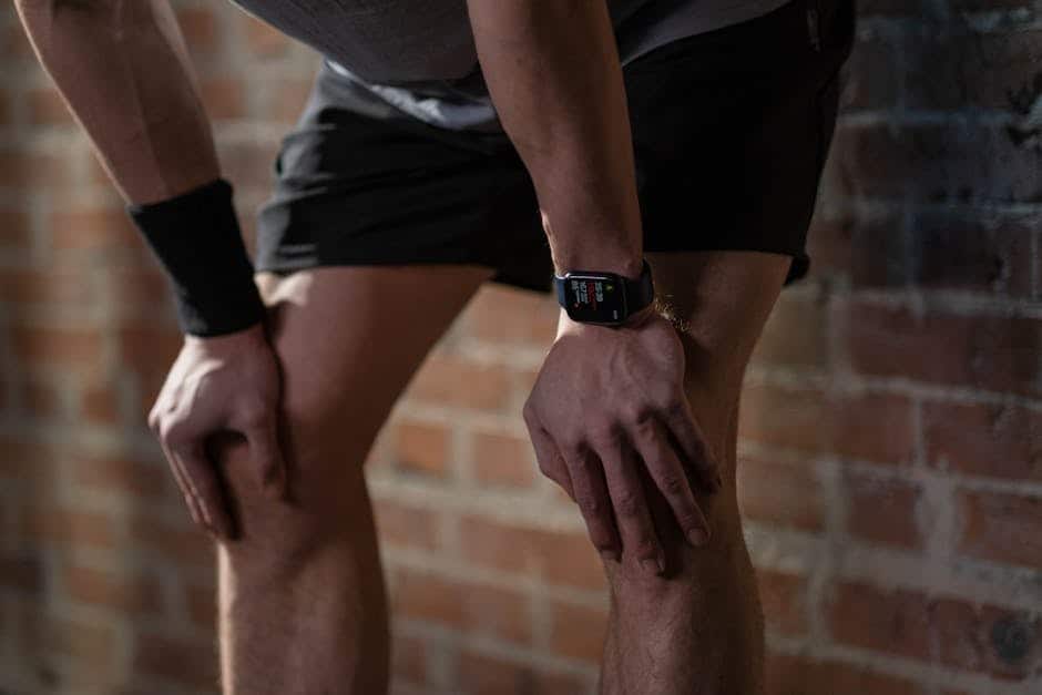 Person, der er træt efter træning, iført smartwatch og sportstøj.