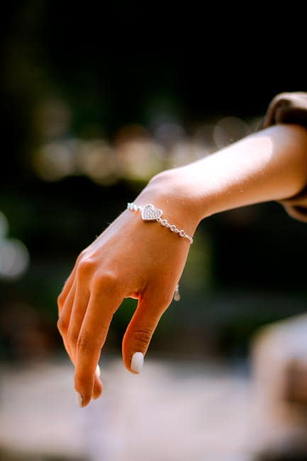 Elegant hånd med smykker, nærbillede af armbånd og ring.