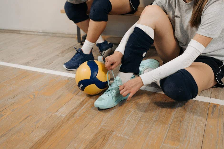 Børn spiller volleyball på indendørs sportsgulv.
