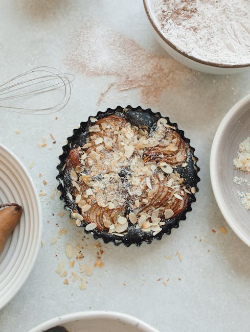 Friskbagt æbletærte med mandler og flødeskum på køkkenbordet.