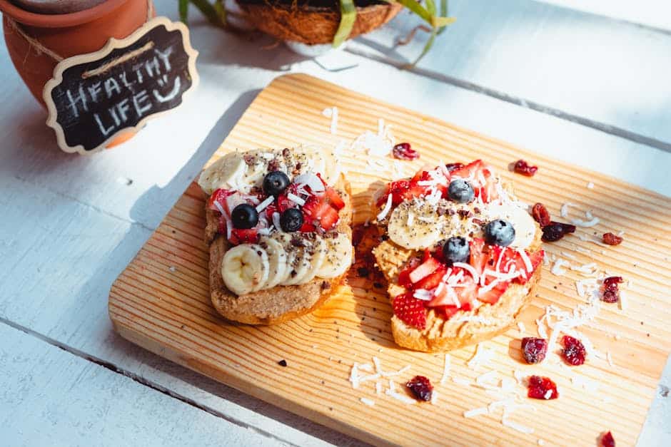 Frisk bagt brød med banan, blåbær og jordbær på træskærebræt.