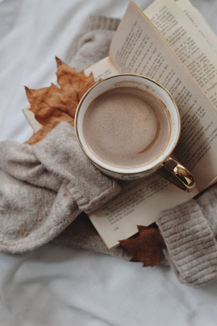 Kaffe i kop med efterårsblade og åben bog, perfekt til afslapning og hygge.