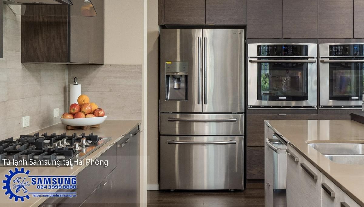 Stainless steel Samsung side-by-side refrigerator in modern kitchen with built-in ovens and gas stove, showcasing professional appliance repair service in Hai Phong.