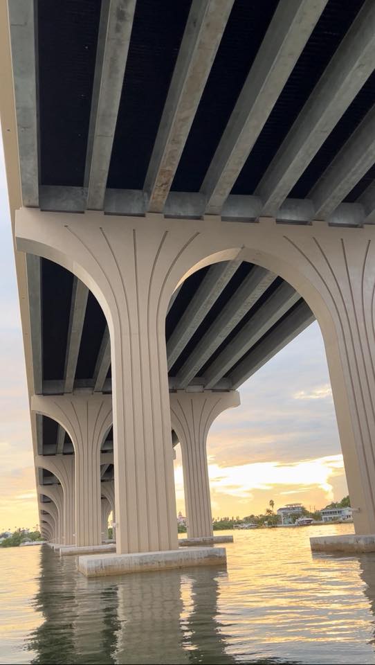 View from beneath a Florida highway bridge, Y-shaped pylons framing a golden sunset.