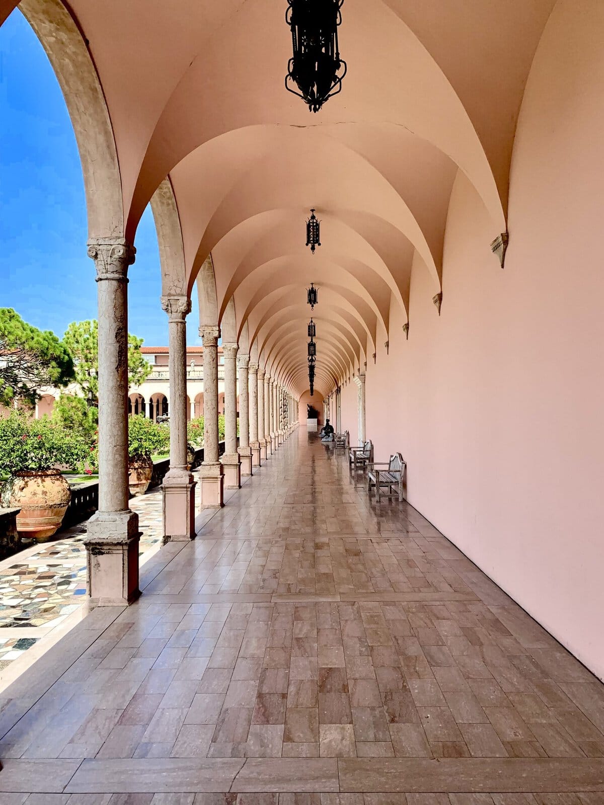 Sunlit loggia at Ringling Museum, Sarasota, with terracotta arches and white classical columns.