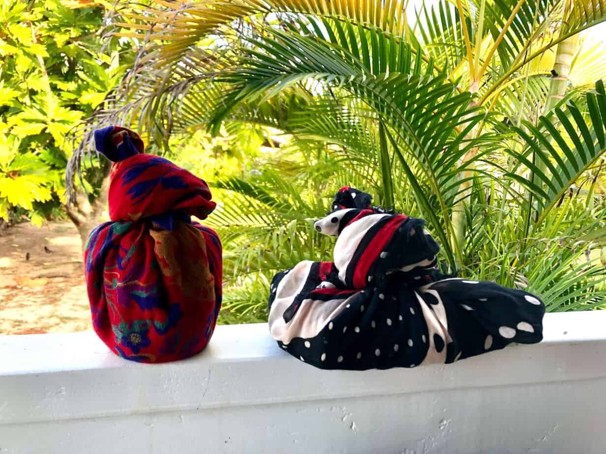 Low waste gifts wrapped in second hand cloth. They are in front of palm leaves.