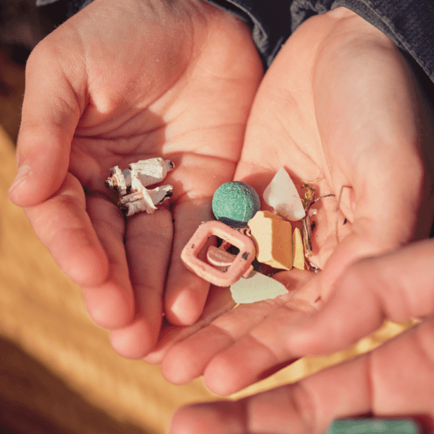 A kid holding micro plastics for a art project using plastic