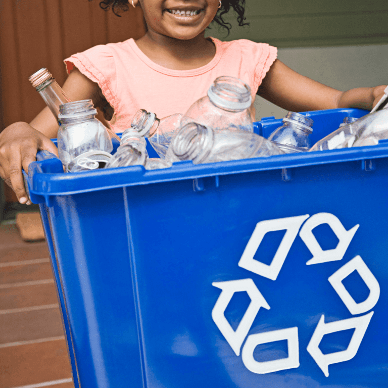 black child holding a recycling bin with plastic bottles in it