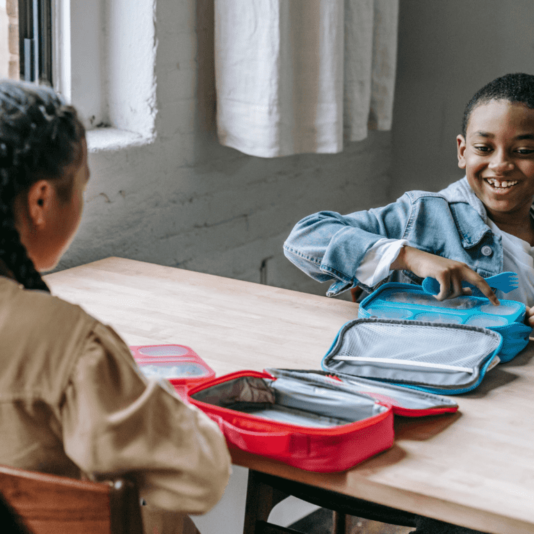Two kids sitting with their lunches which represents vegan lunches for kids