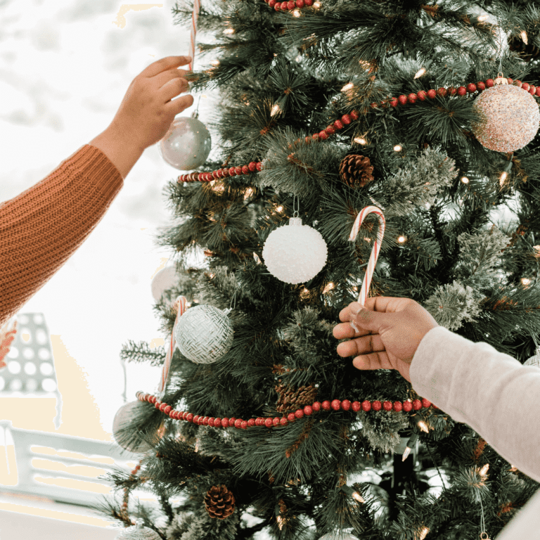 two people decorating a christmas tree