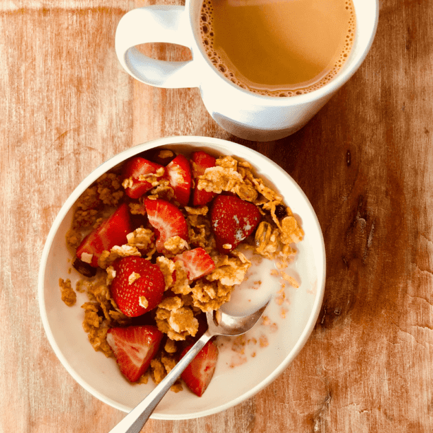 A bowl of cereal with strawberries and protein rich cereal.