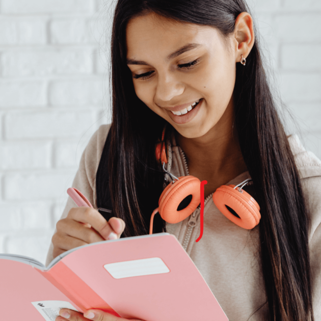 a teenager listening to her headphones and writing in a journal for self care