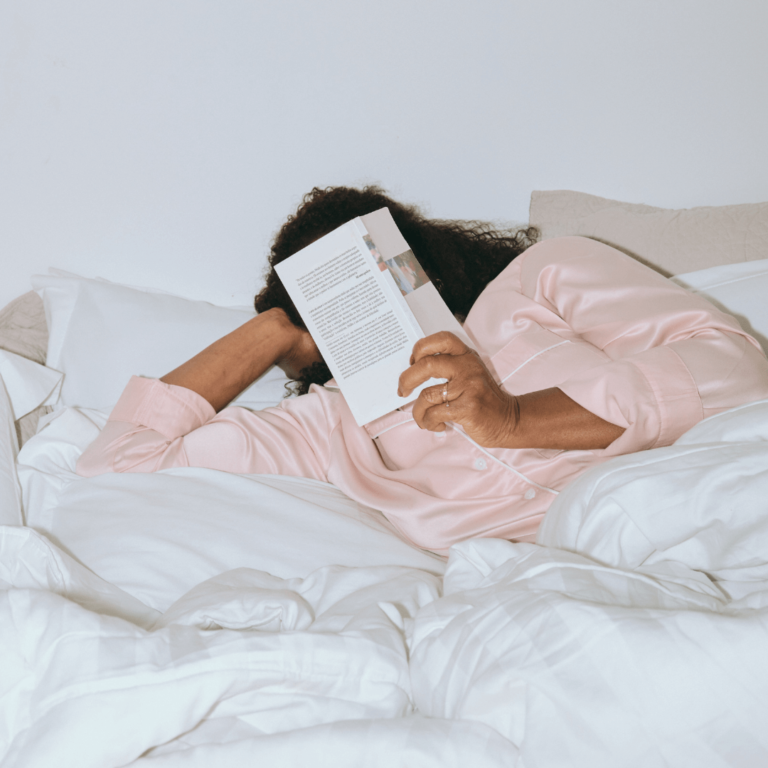 a woman laying in bed reading a book as a part of her evening routine