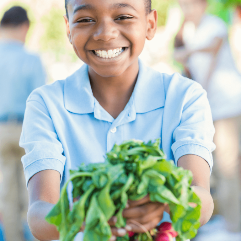 elementary school child holding a radish from working in his school garden