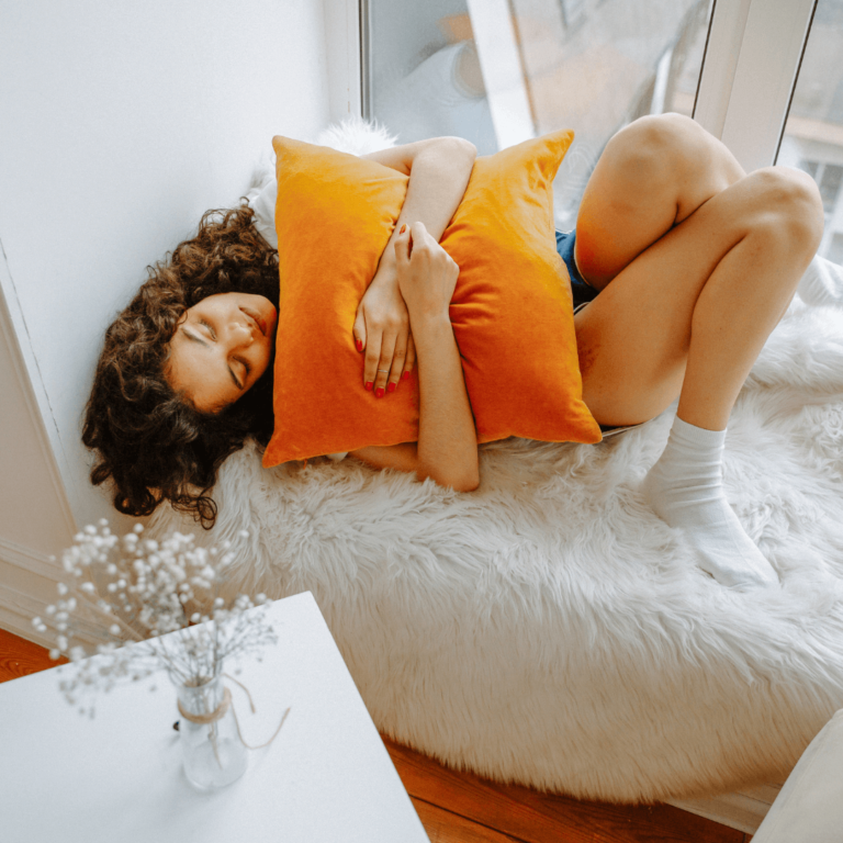 a girl laying on the couch with cramps experiencing her period