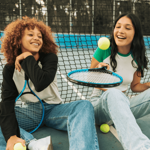 two teens girls doing a healthy hobby, playing tennis together