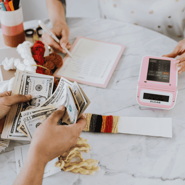 two people sitting down working on their budget for the month to save money