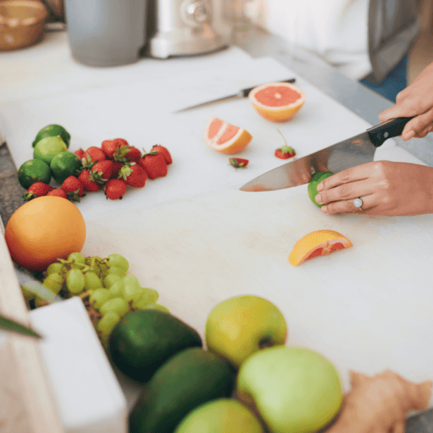 a person cutting up produce for a homemade juice