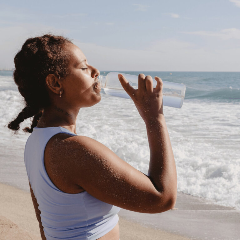 a woman drinking out of her reusable water bottle