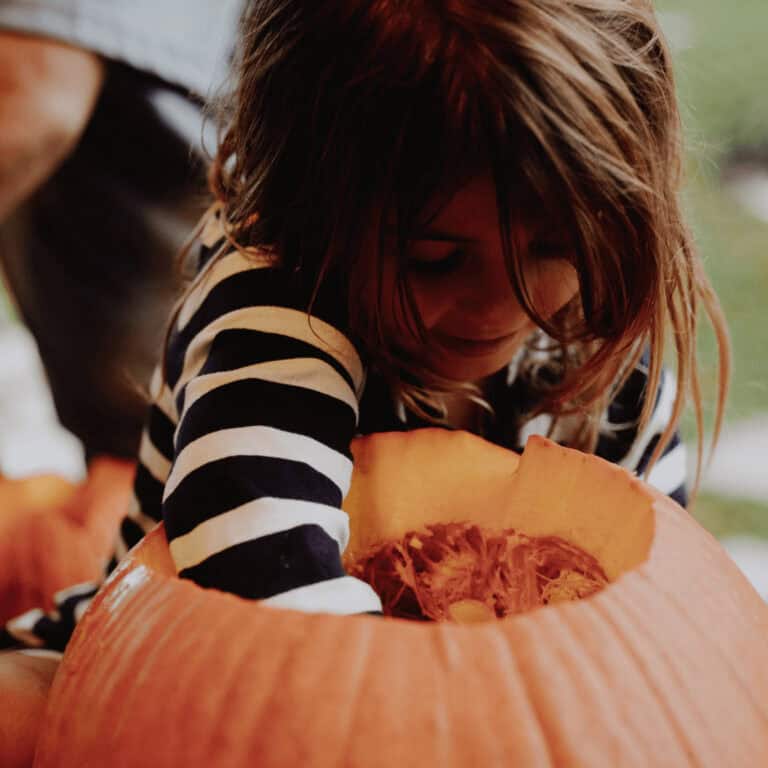 a kid carving a pumpkin for sustainable home decor