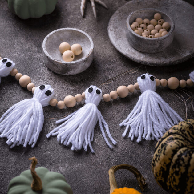 a homemade ghost garland made from yarn and wood