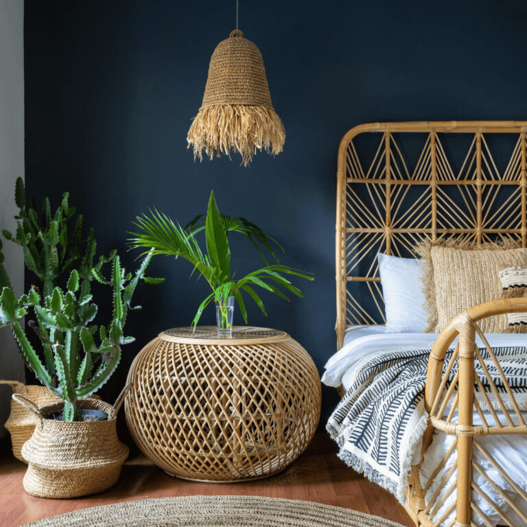 a small bedroom with a rattan side table, baskets for plants and rattan bed frame