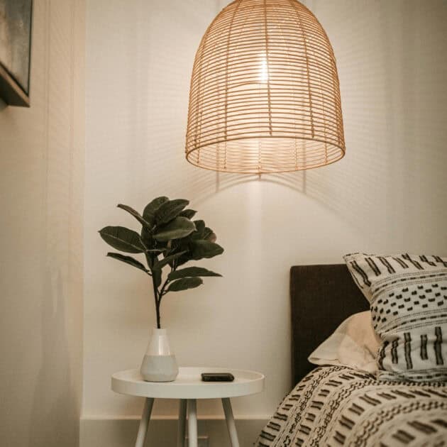 rattan light and a plant on a bedside table