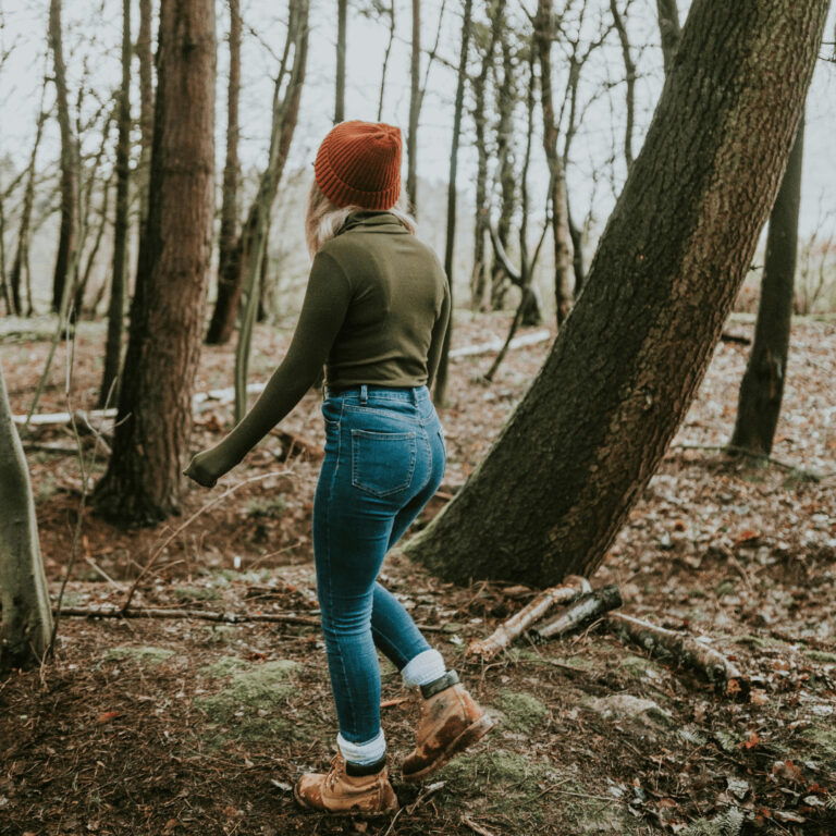 casual fall hiking outfit with orange beanie, long sleeve shirt, jeans and hiking boots