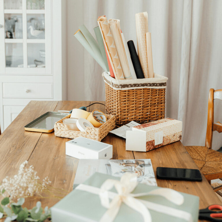 a basket holding wrapping paper and a box holding wrapping ribbon
