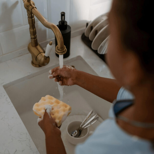 someone washing dishes in a kitchen sink