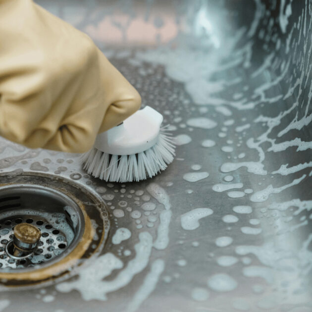 a person deep cleaning a kitchen drain