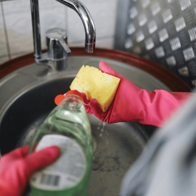sponge, dish soap, cleaning gloves and a kitchen sink
