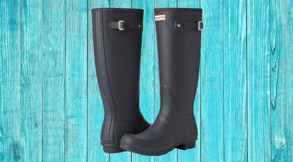 Black rain boots on a teal wood background