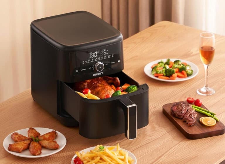 Air fryer cooking chicken and vegetables on table.