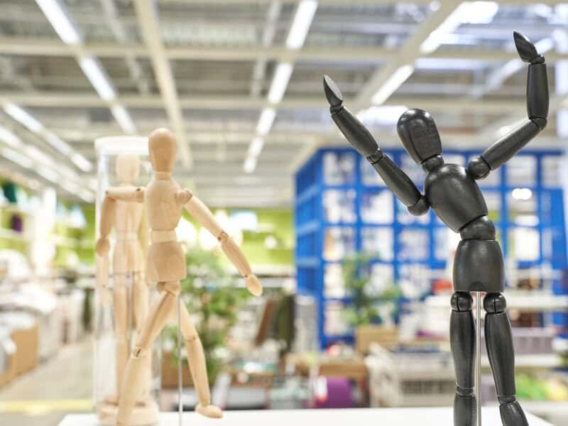 Wooden mannequins displayed in a store aisle.