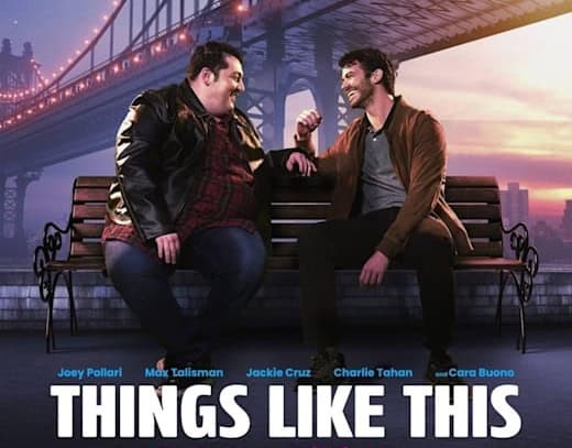 Two men smiling on bench, bridge in background.