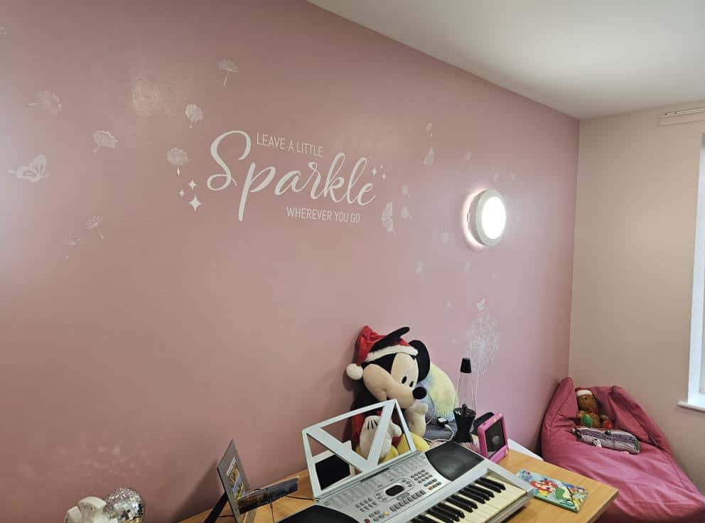 Interior wall painted pink with Minnie Mouse plush and wall quote, professional decorators in action.