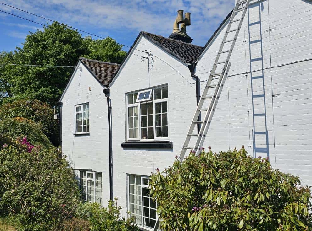 White painted house exterior with ladder, professional decorators, residential painting services.