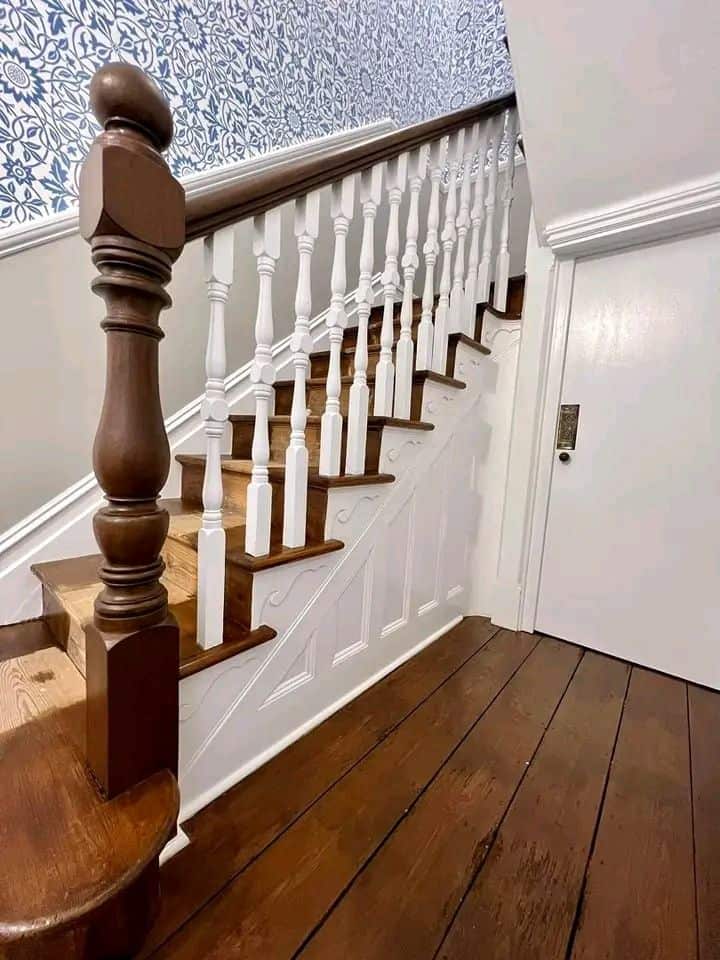 Interior staircase painted with white spindles and wooden handrail, showcasing professional decorati.