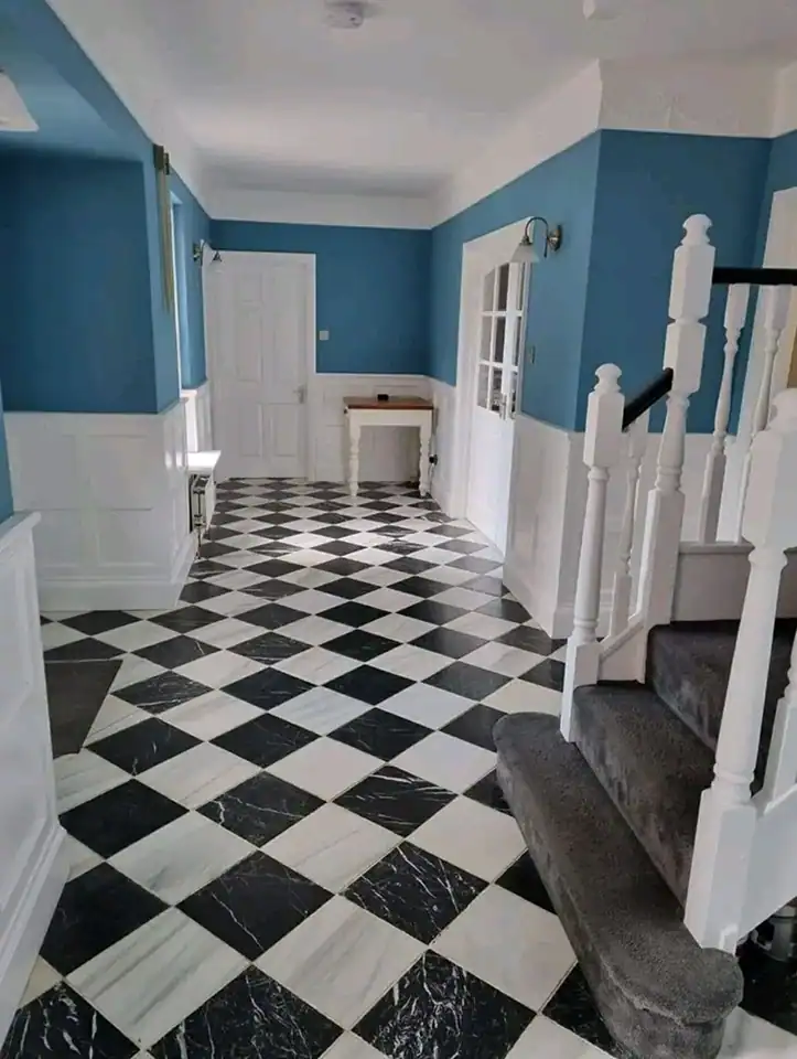 Blue interior walls with white trim and staircase, featuring a stylish black and white checkered mar.