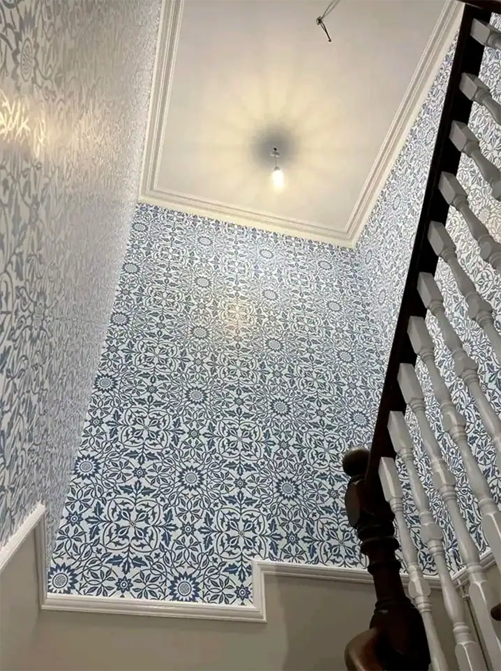 Interior wall with intricate blue and white patterned wallpaper in a residential staircase area.