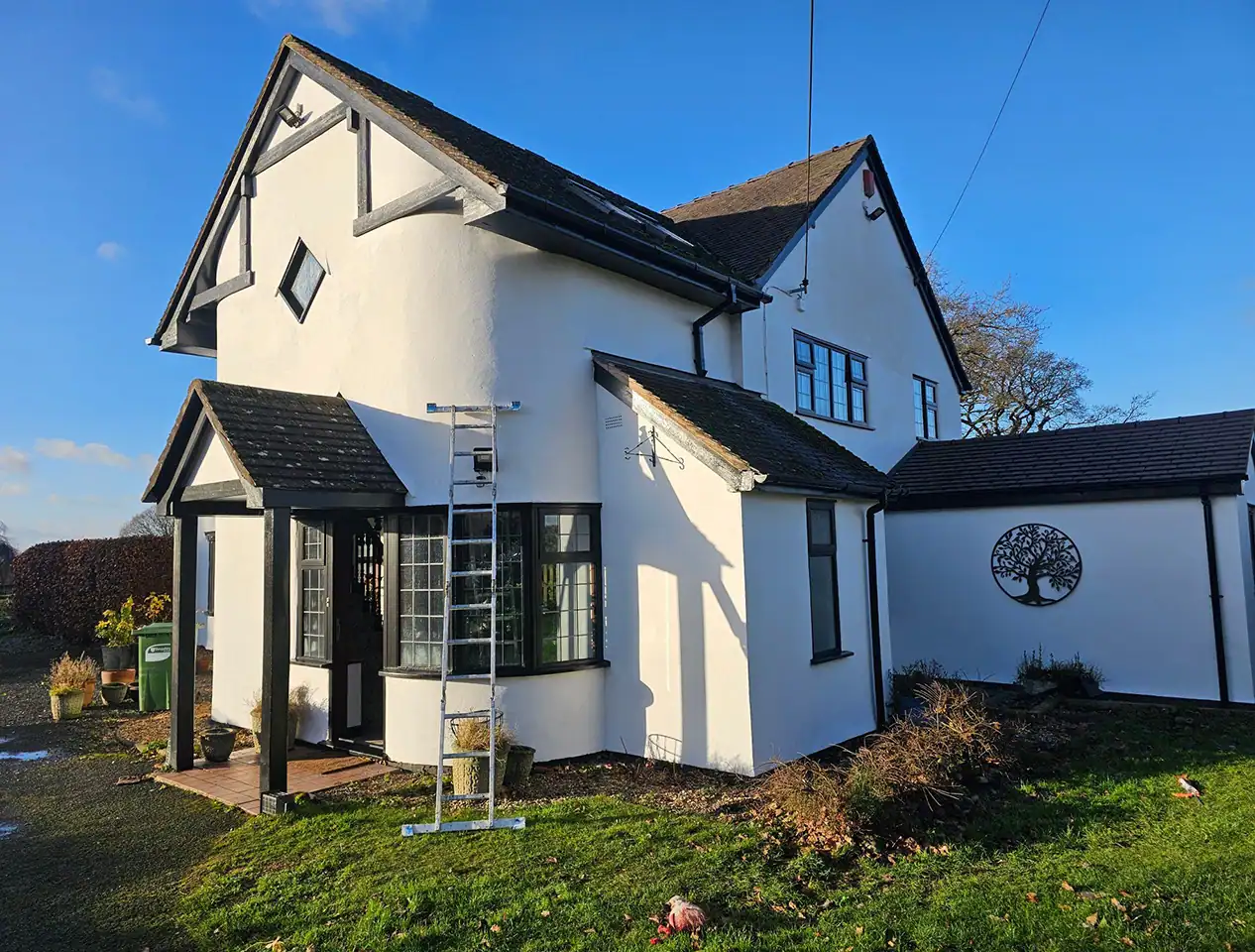 Painted white house exterior with black window frames and roof, completed by professional decorators.