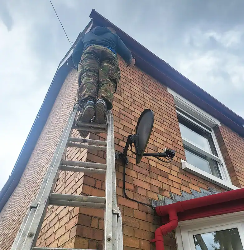 Skilled painter working on the exterior brick wall of a house from a ladder.