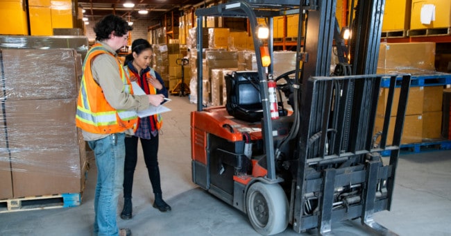 4 Ultimate Forklift Safety Tips 2 people standing next to a forklift