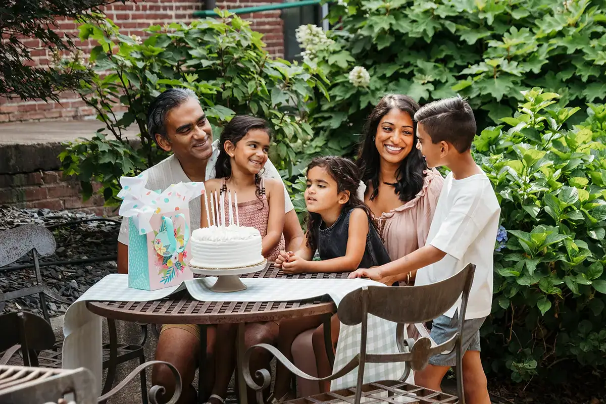 Family celebrating a birthday outdoors with cake, photographed using a Tamron RF mount lens on a Canon EOS mirrorless camera.