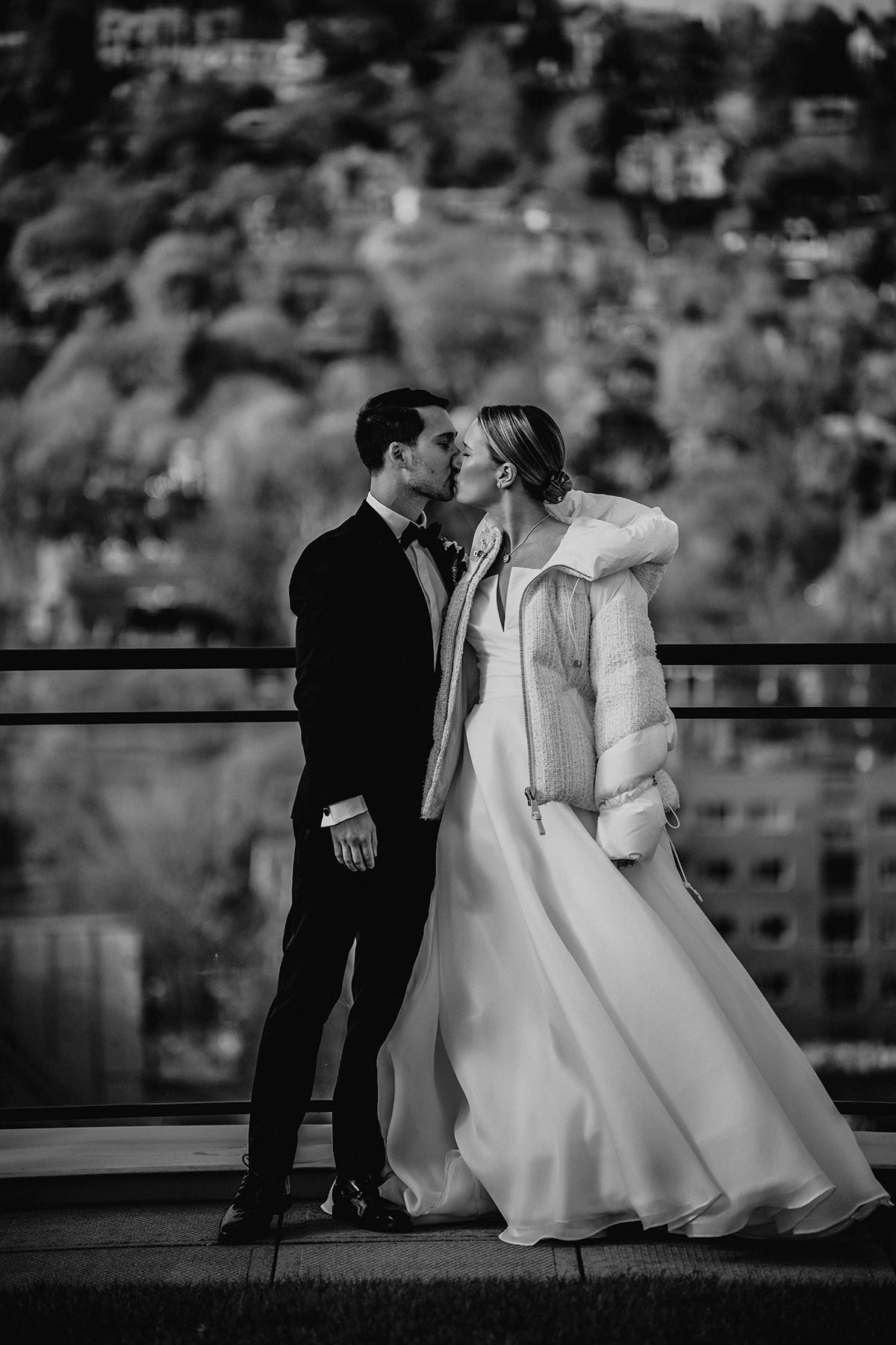 La mariée et le marié partagent un baiser en plein air lors d'un mariage hivernal, capturé dans un noir et blanc saisissant avec l'un des meilleurs objectifs de photographie événementielle. ©Rabih Madi