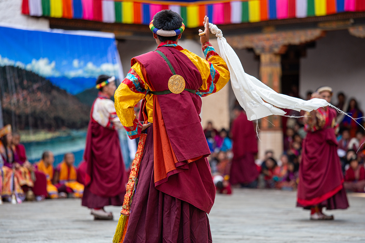 Un artiste de festival traditionnel, vêtu d'une tenue de cérémonie éclatante, danse devant la foule, illustrant la richesse culturelle et l'énergie captées lors de la photographie de concerts et de festivals.
