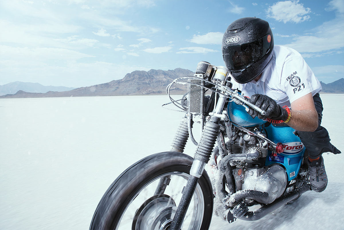 Motocycliste en tenue complète traversant une étendue de sel blanc, capturé en flou de mouvement à l'aide d'une technique de panoramique - idéal pour les conseils de photographie d'action à moto.