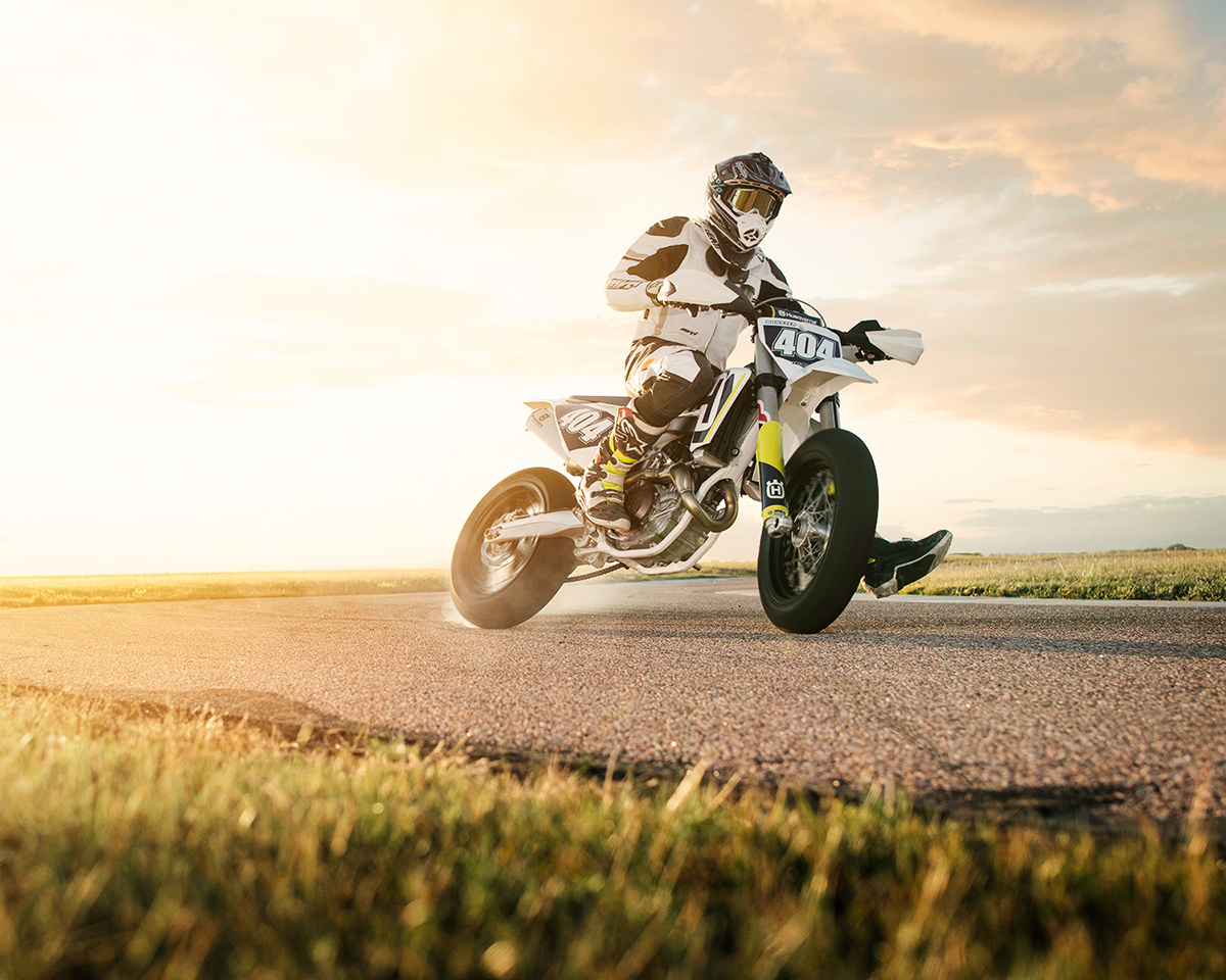 Motocycliste dérivant sur l'asphalte au coucher du soleil, capturé avec l'éclairage de l'heure dorée - mettant en évidence les conseils de photographie de moto pour un mouvement dynamique.